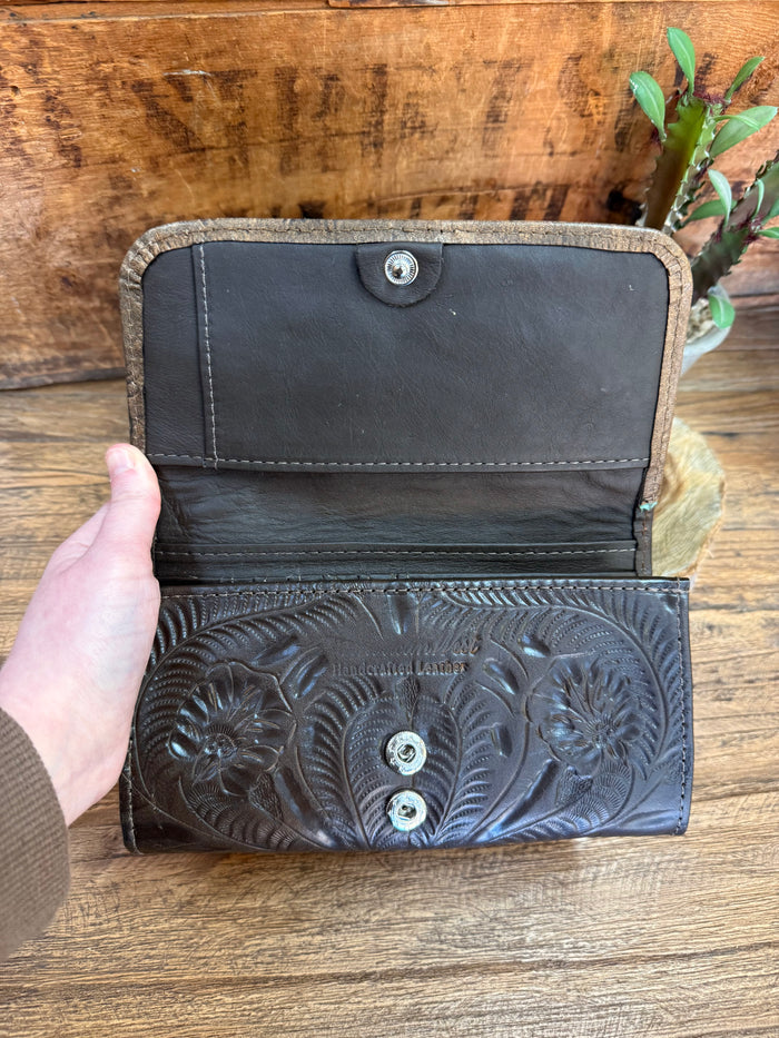 Open dark leather wallet with snap closure and embossed floral front panel