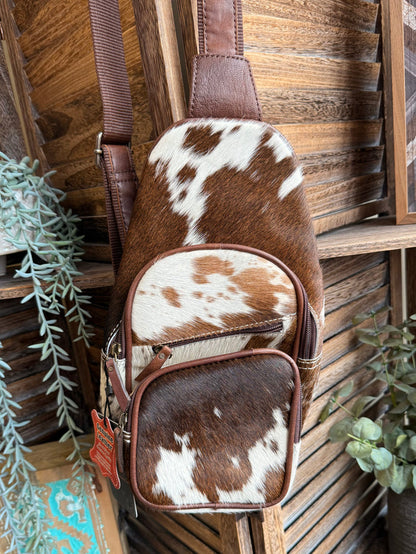 Cowhide fanny pack sling bag with adjustable strap and two cow-print zip compartments