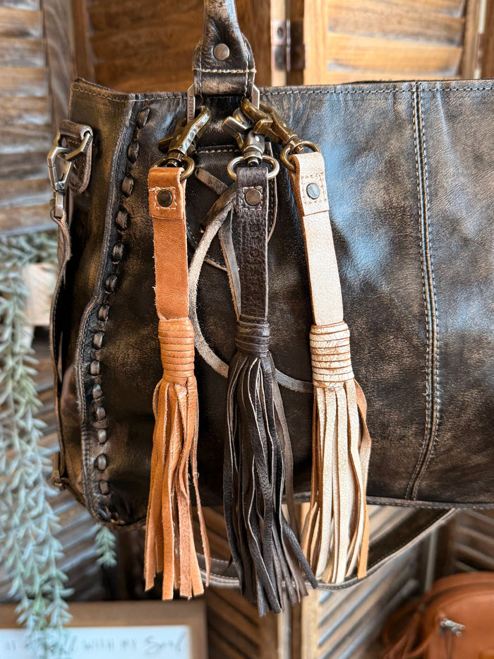 Leather tote with multiple leather tassel clips in dark, tan, and caramel colors
