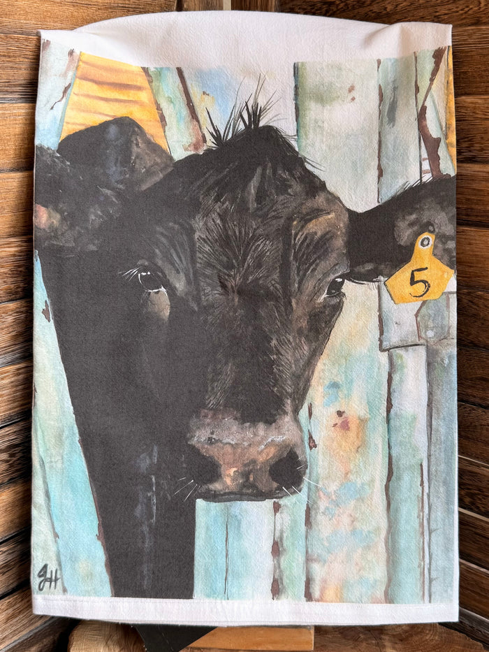 Watercolor cow tea towel featuring black cow head and yellow 5 tag detail