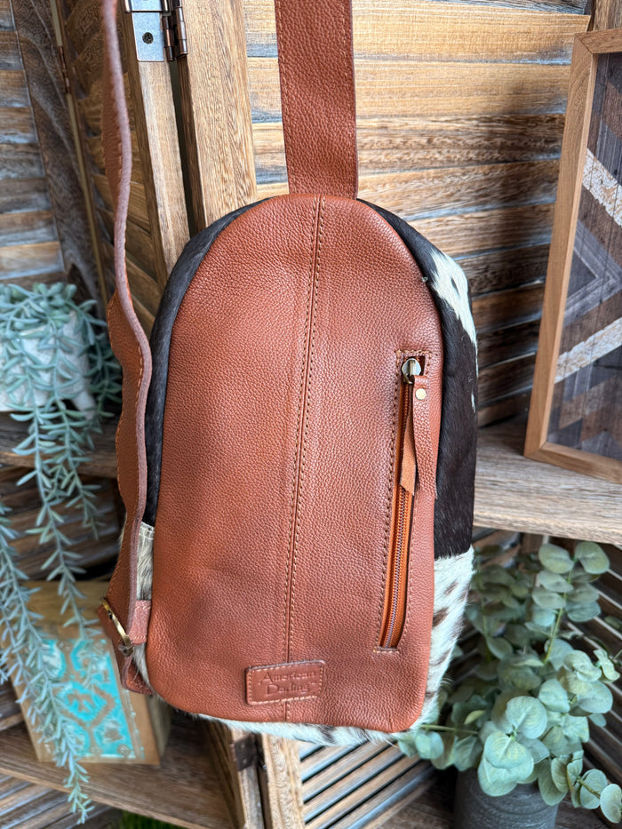 Brown leather sling bag back panel with zip pocket and adjustable strap