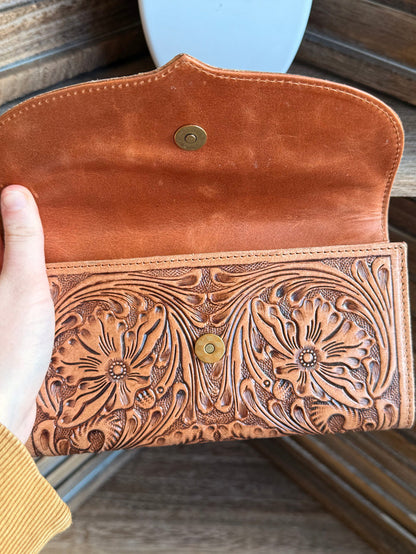 Open brown leather flap wallet with floral tooling and round metal snap buttons.