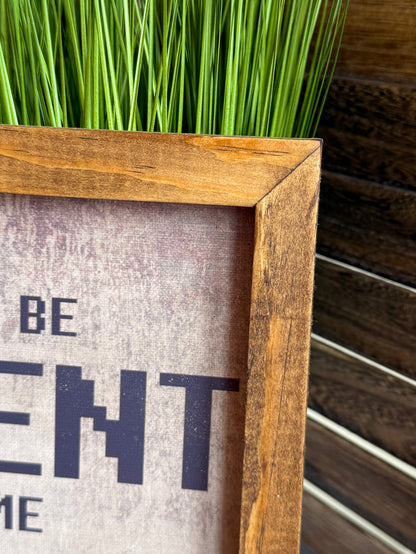 Close-up of wood-framed wall art with large “PATIENT” lettering on a light background