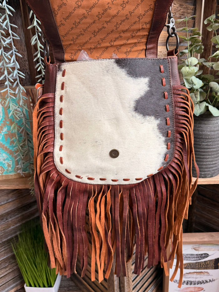 Cowhide crossbody purse with white cowhide flap and fringe tassels in brown