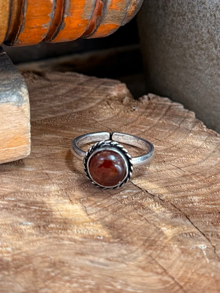 Silver adjustable ring featuring a red round stone in an ornate bezel