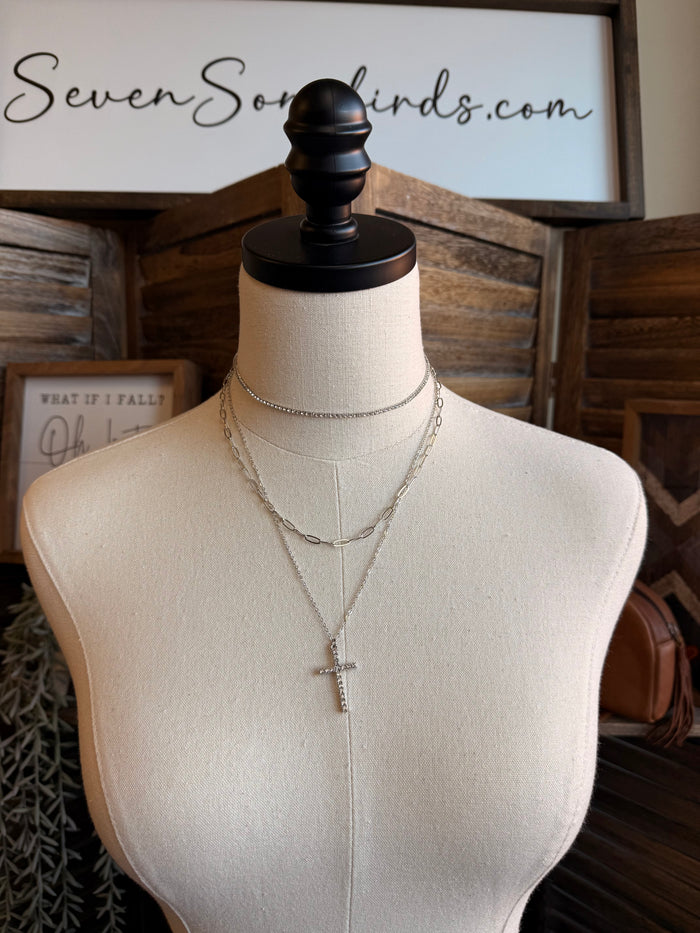 Silver cross pendant necklace set on a mannequin with two stacked chains