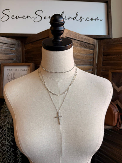 Silver cross pendant necklace set on a mannequin with two stacked chains