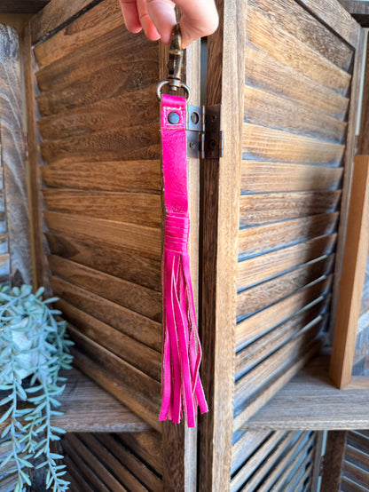 Fuchsia pink leather tassel clip with metal clasp and hanging fringe on a key ring