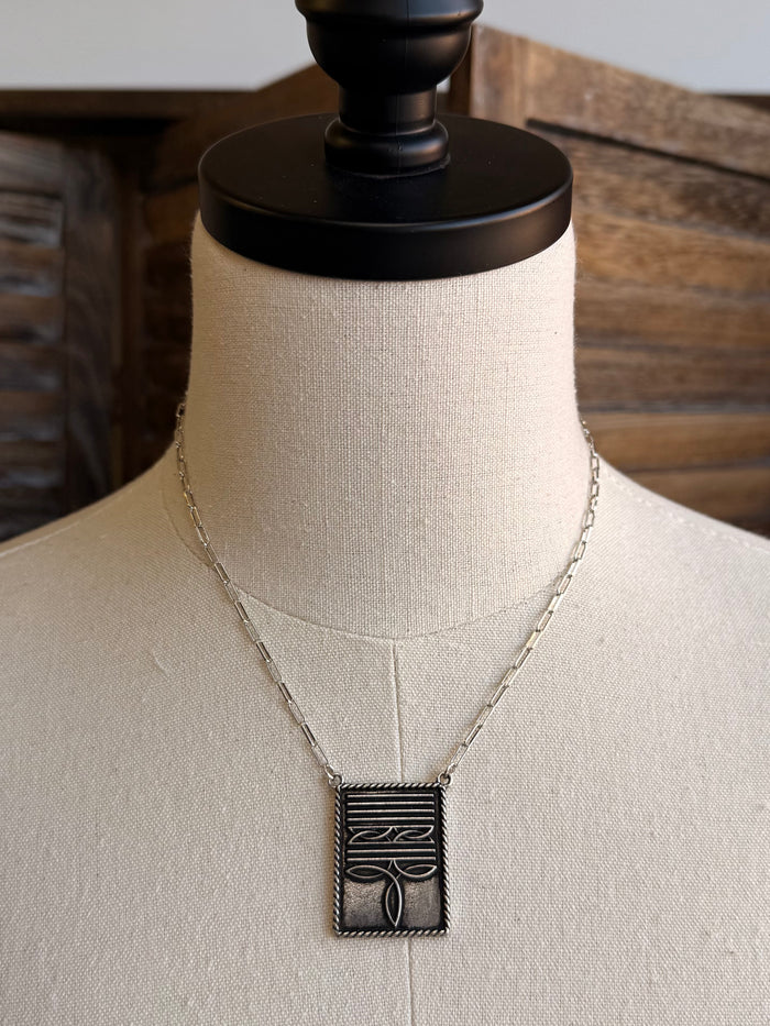 Silver-tone necklace with rectangular boot-stitch pendant and linked chain