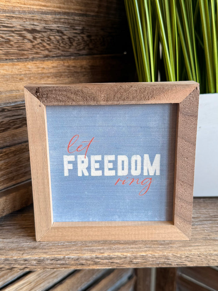 Wooden-framed 4x4 artwork with blue background and red/white “FREEDOM ring” text