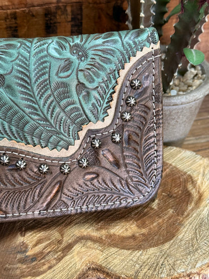 Turquoise leather tooled wallet close-up with floral embossing and silver-tone studs