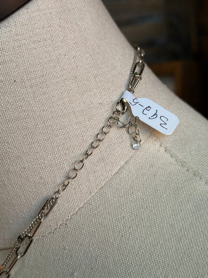 Silver chain necklace with rectangular pendant and small engraved tag on a short extender