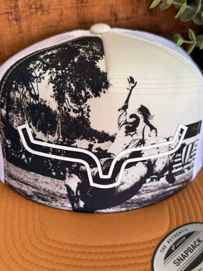 Beige trucker cap close-up with black-and-white western scene on front panel
