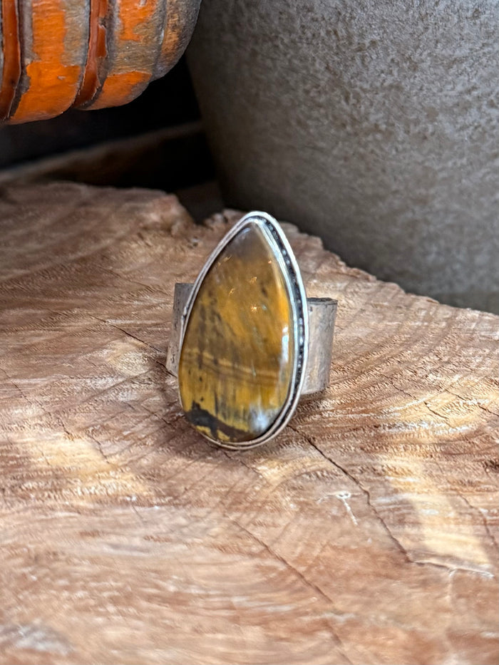 Adjustable stone ring with oval yellow cabochon set in silver-toned frame