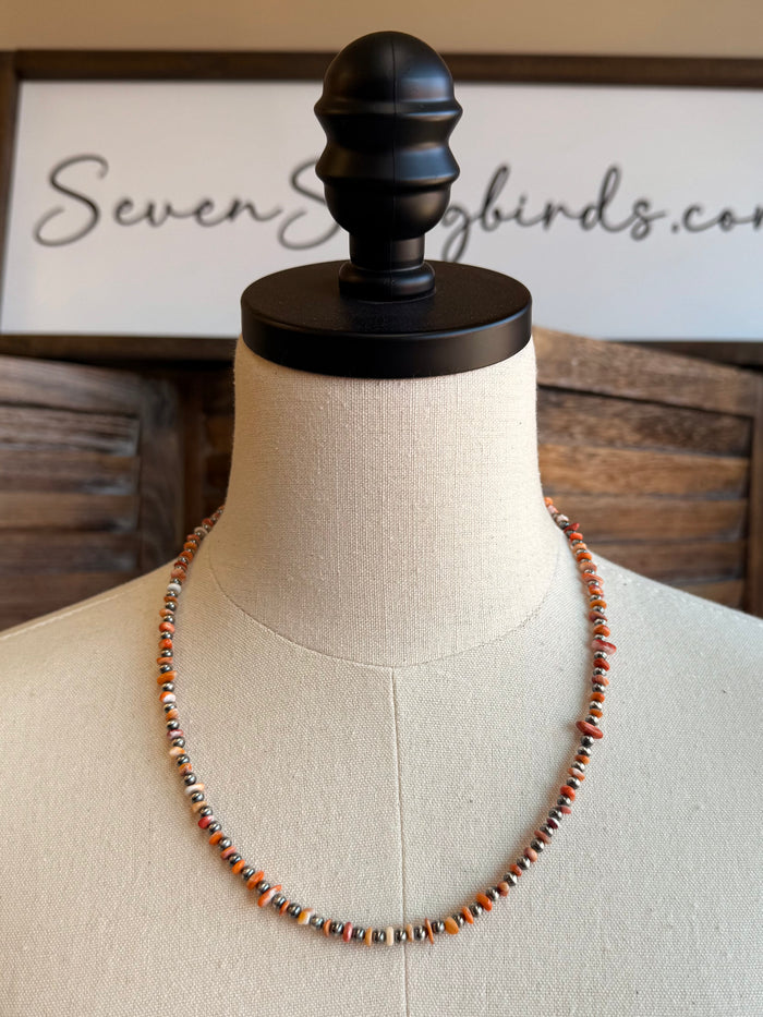 Orange spiny oyster chip necklace with sterling silver beads, draped on mannequin