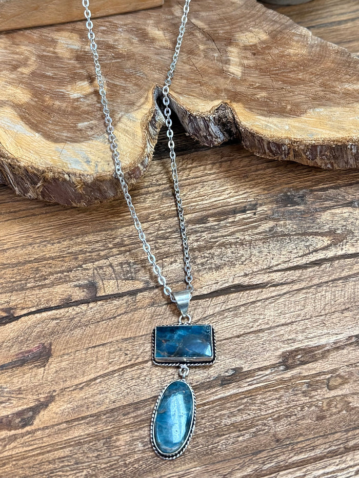 Silver lariat necklace with blue rectangular and oval stone pendants connected by chain