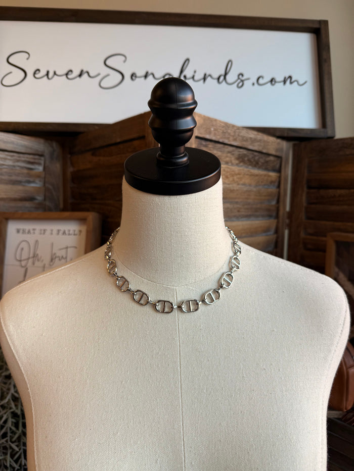 Silver bottle-cap link necklace on a mannequin display
