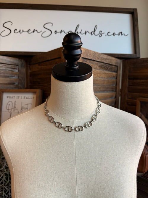 Silver bottle-cap link necklace on a mannequin display