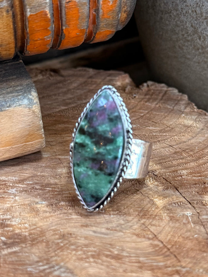 Large oval green gemstone ring with silver-tone band and raised side setting