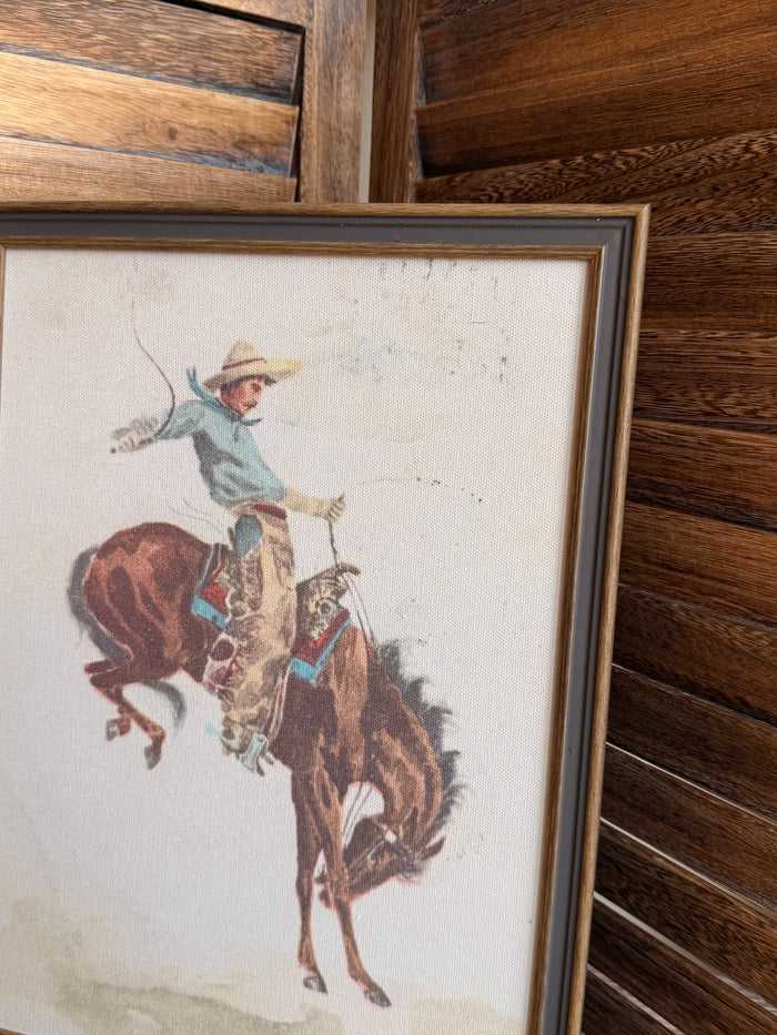 Framed cowboy on bucking bronco print, dark wood frame, angled view