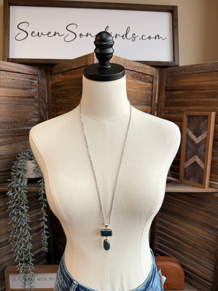 Silver-plated lariat style necklace on mannequin with blue rectangle and oval pendants