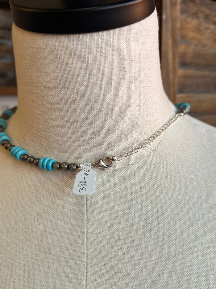 Turquoise bead strand necklace detail with silver chain, clasp, and small charm tag