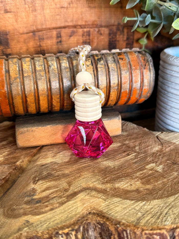 Mini reed diffuser with clear bottle, white stacked discs, and pink faceted base