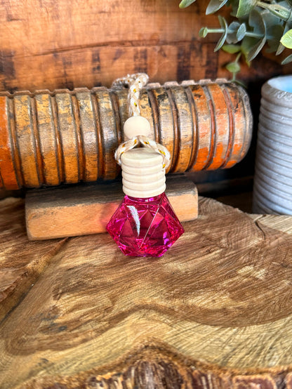 Mini reed diffuser with clear bottle, white stacked discs, and pink faceted base
