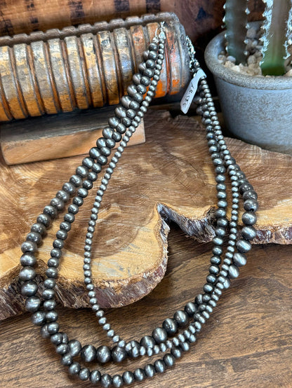 Triple-strand beaded necklace with dark metallic pearls, layered strand design