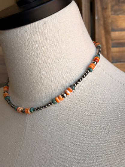 Close-up of turquoise and orange beads on a silver-tone necklace chain