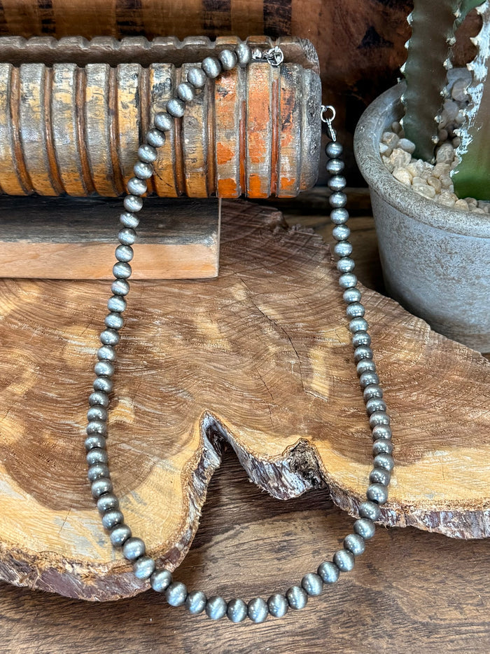 20-inch pearl necklace featuring dark blue-gray beads and small metal clasp