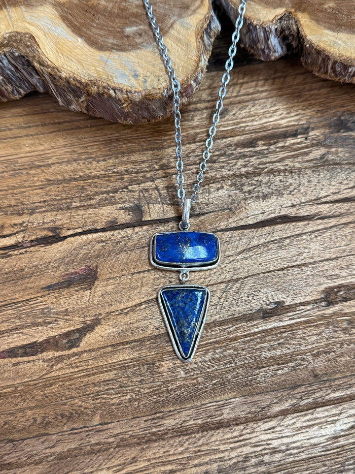 Close-up of silver chain lariat necklace with blue rectangular and teardrop charms