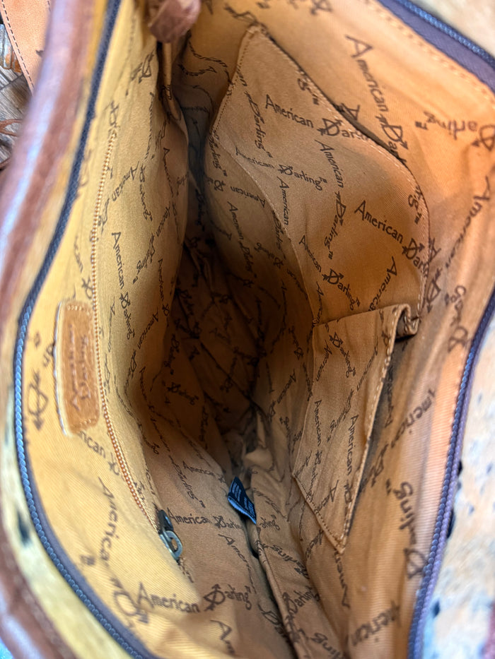 Fringed cowhide crossbody purse interior with tan lining and allover printed text