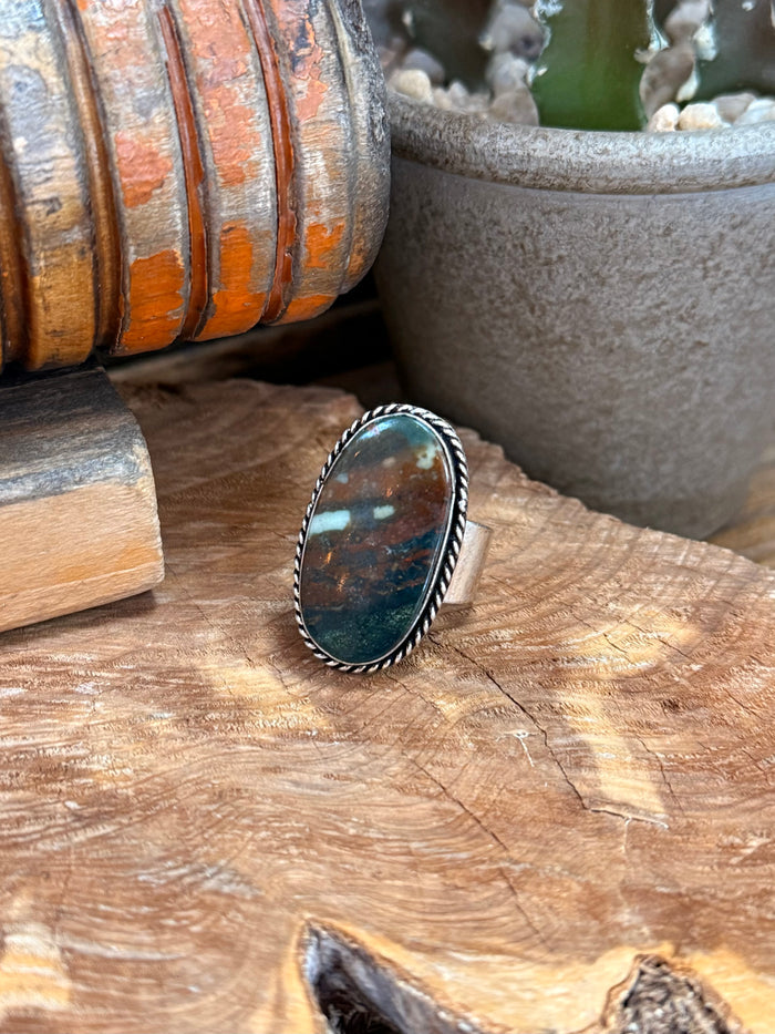 Adjustable oval stone ring with blue-green marbled cabochon and silver braided bezel