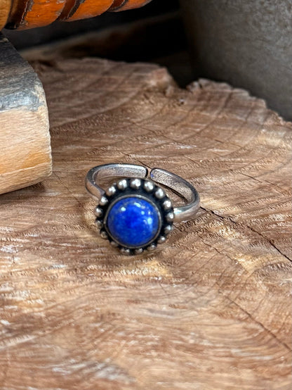 Adjustable silver-tone ring with bezel-set round blue gemstone and raised bead edge