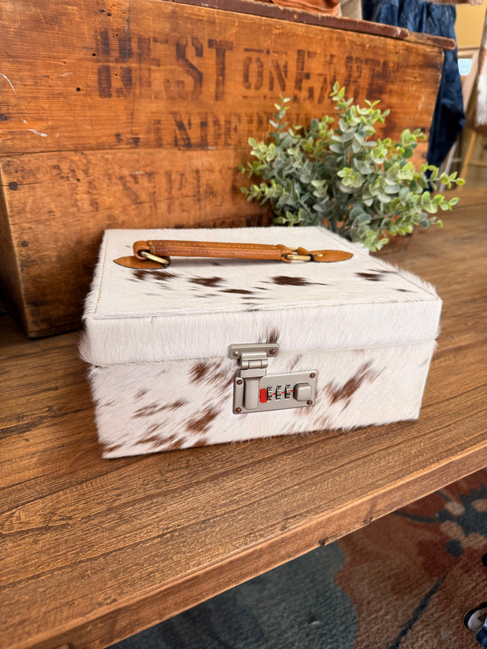 Hair-on cowhide jewelry box with tan leather handle and combination lock on front