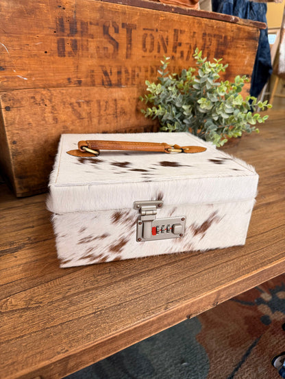 Hair-on cowhide jewelry box with tan leather handle and combination lock on front