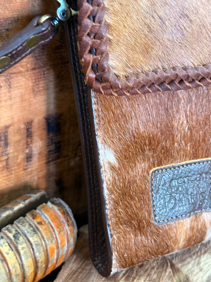 Brown cowhide crossbody pouch bag side with braided trim and embossed leather logo patch