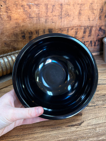 Round black melamine bowl interior, glossy finish held in hand