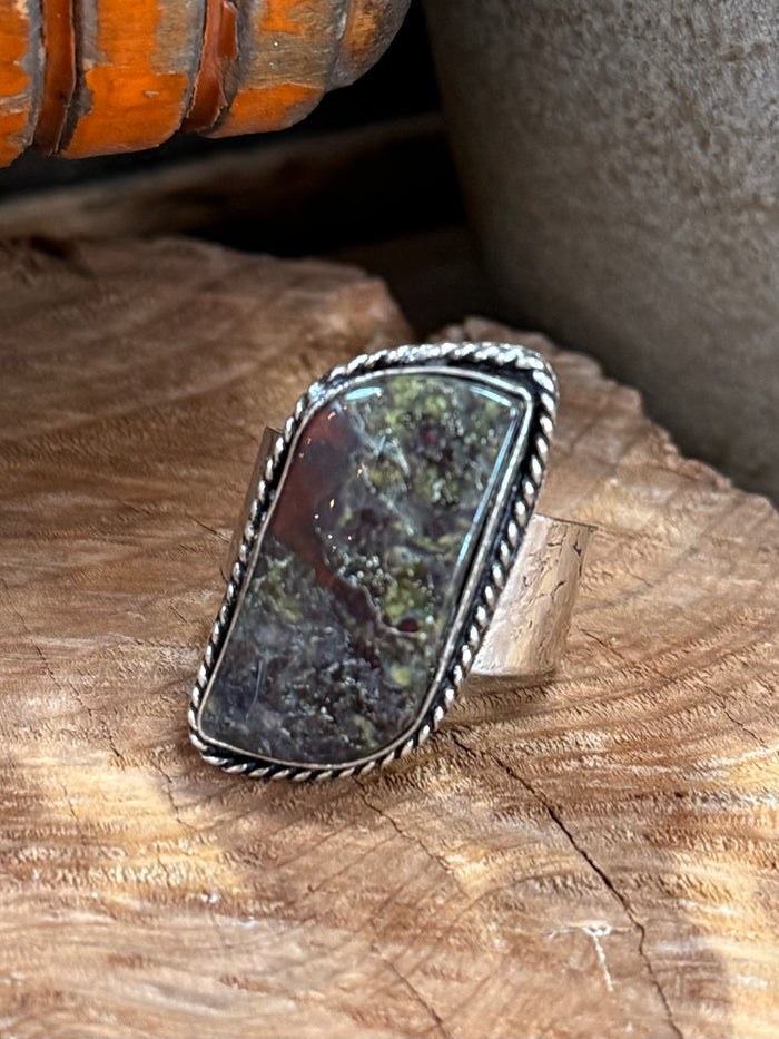 Shield-shaped cabochon stone ring with silver-tone band and textured frame