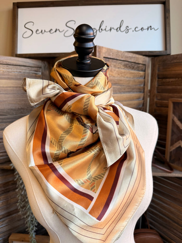 Wild rag scarf draped on mannequin, beige with rust and orange letter geometric print