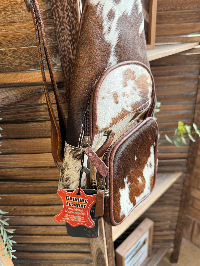 Cowhide sling bag with American Darling tag and cow-print side zip pocket