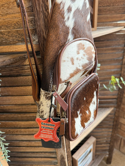 Cowhide sling bag with American Darling tag and cow-print side zip pocket