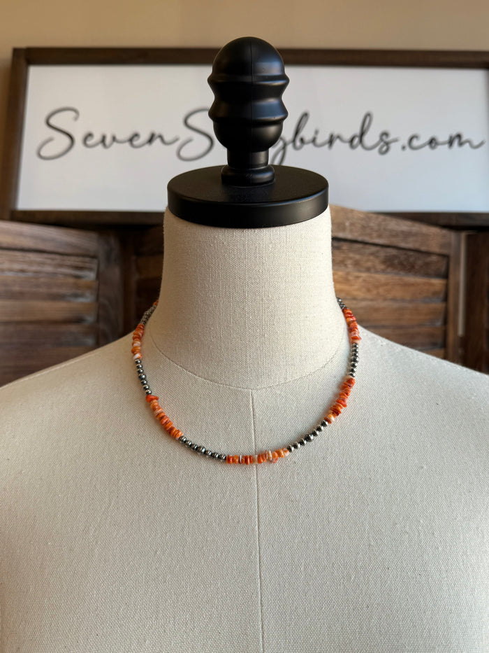 Orange spiny oyster chip necklace on mannequin, silver-tone beaded strand