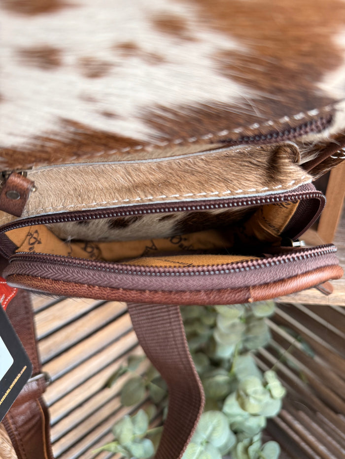 Cowhide sling bag close-up of stitched zipper seam and patterned interior lining