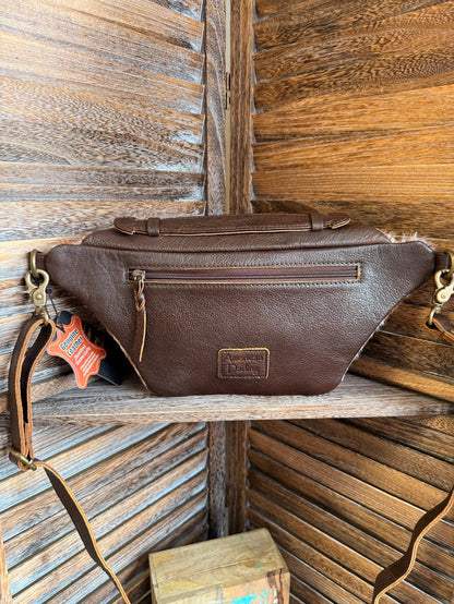 Brown leather fanny pack with zip top, braided trim, and strap with metal clips