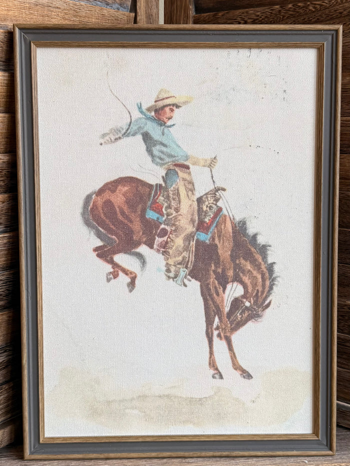 Framed cowboy on bucking bronco print with beige mat and dark wood frame