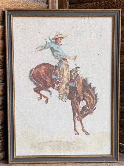 Framed cowboy on bucking bronco print with beige mat and dark wood frame