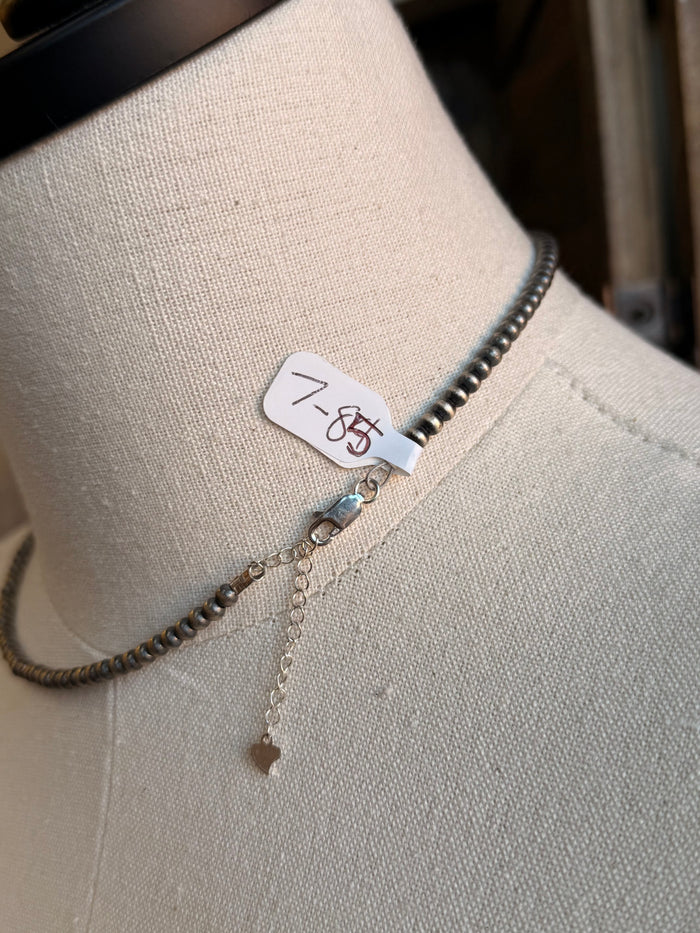 Sterling silver necklace with clasp tag and small dangling charm below