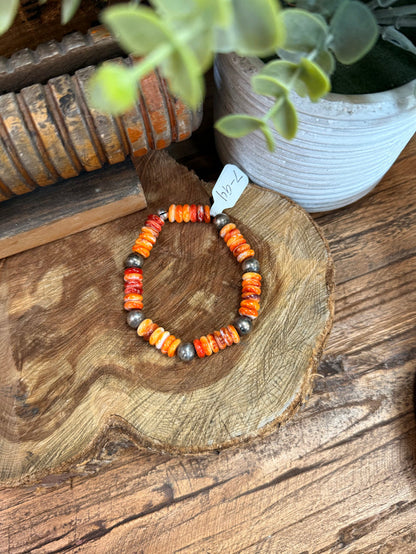 Orange and white beaded stretch bracelet with metallic gray spacer beads and rounded bead texture